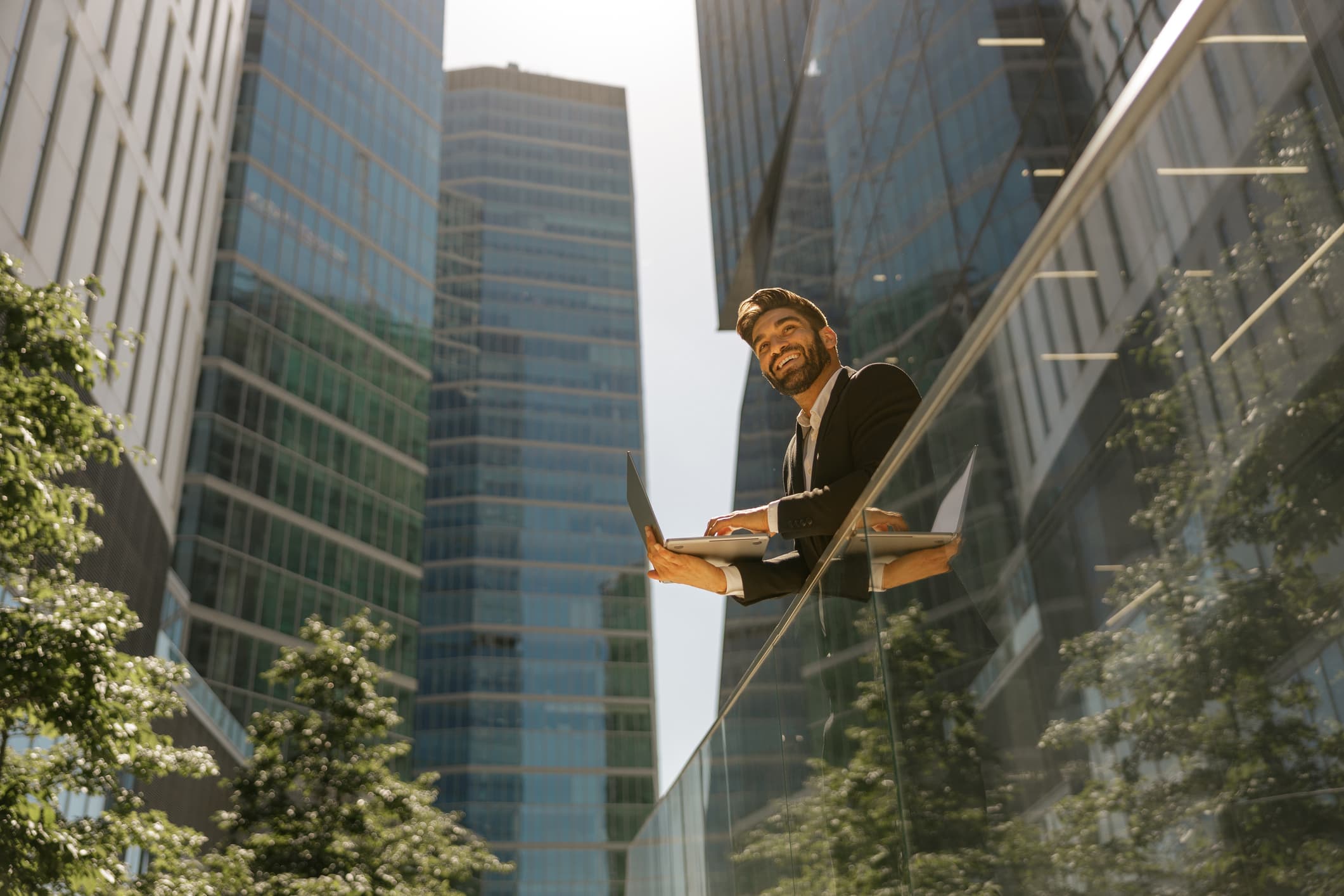 Man working on laptop standing on office terrace in the city.